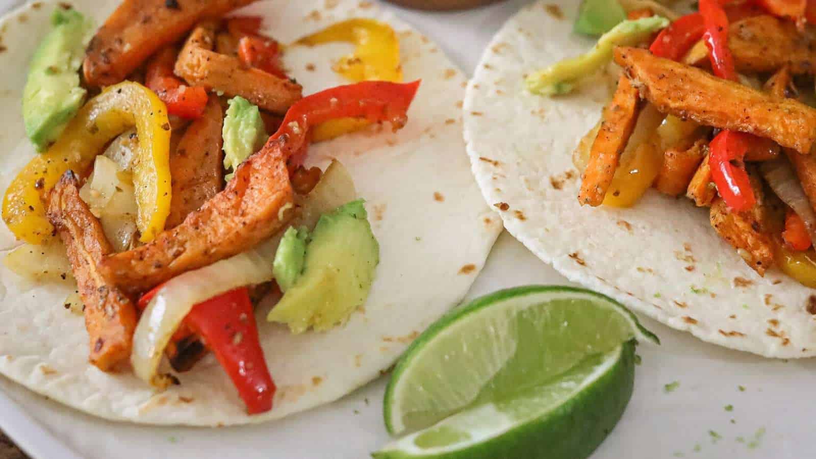 A close up of sweet potato fajitas on a platter with fresh lime.