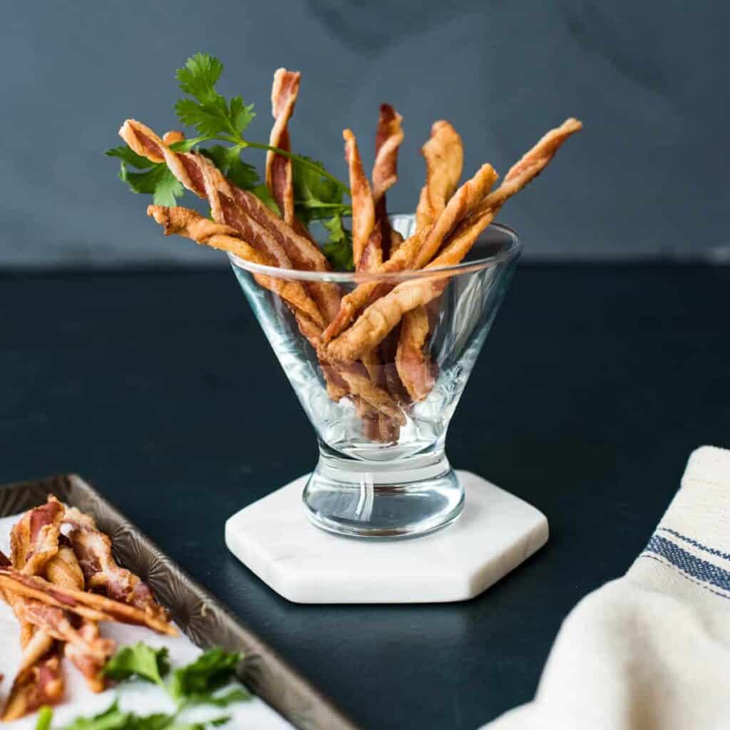 Bacon sticks in a glass bowl with parsley.