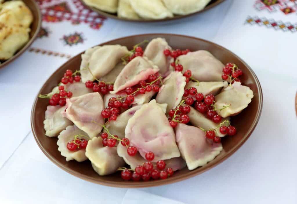 Traditional Ukrainian dumplings with berries on a table.