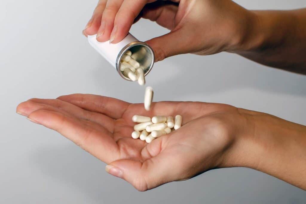 A person pouring probiotic pills into their hand.
