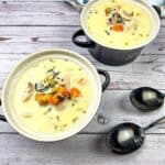 Two bowls of creamy chicken & wild rice soup on a wooden table.