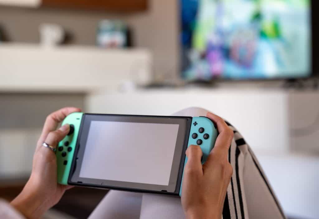 A woman playing cozy games on a Nintendo Switch in front of a TV.