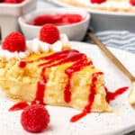 A slice of lemon sponge pie with raspberries and whipped cream.