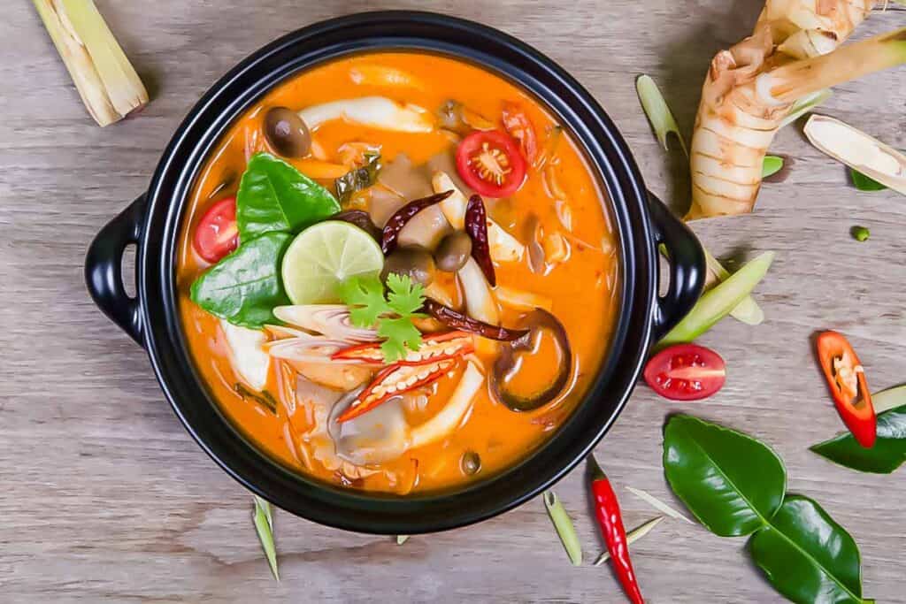 A bowl of thai curry on a wooden table.