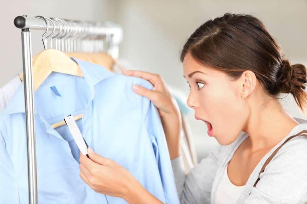 A woman is looking at a shirt hanging on a rack.