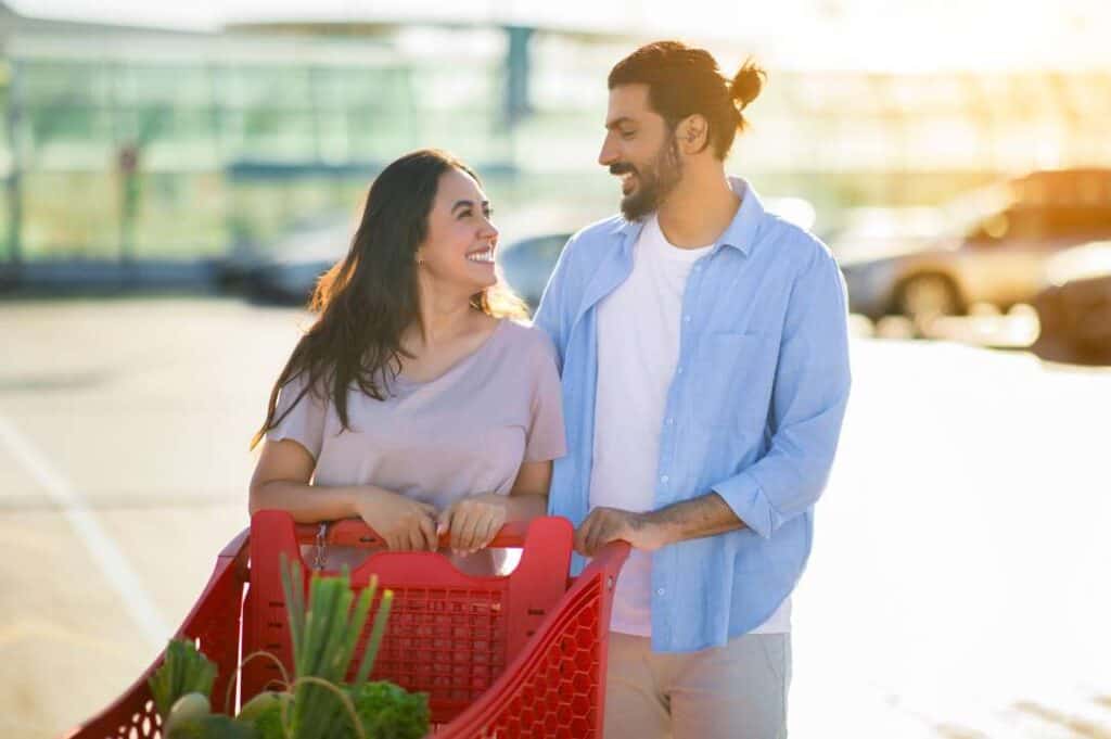 A couple holding a shopping cart in a parking lot.