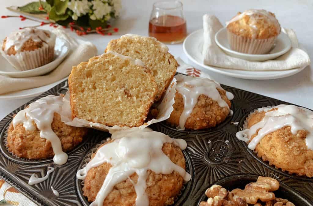 A tray of muffins with icing and walnuts.