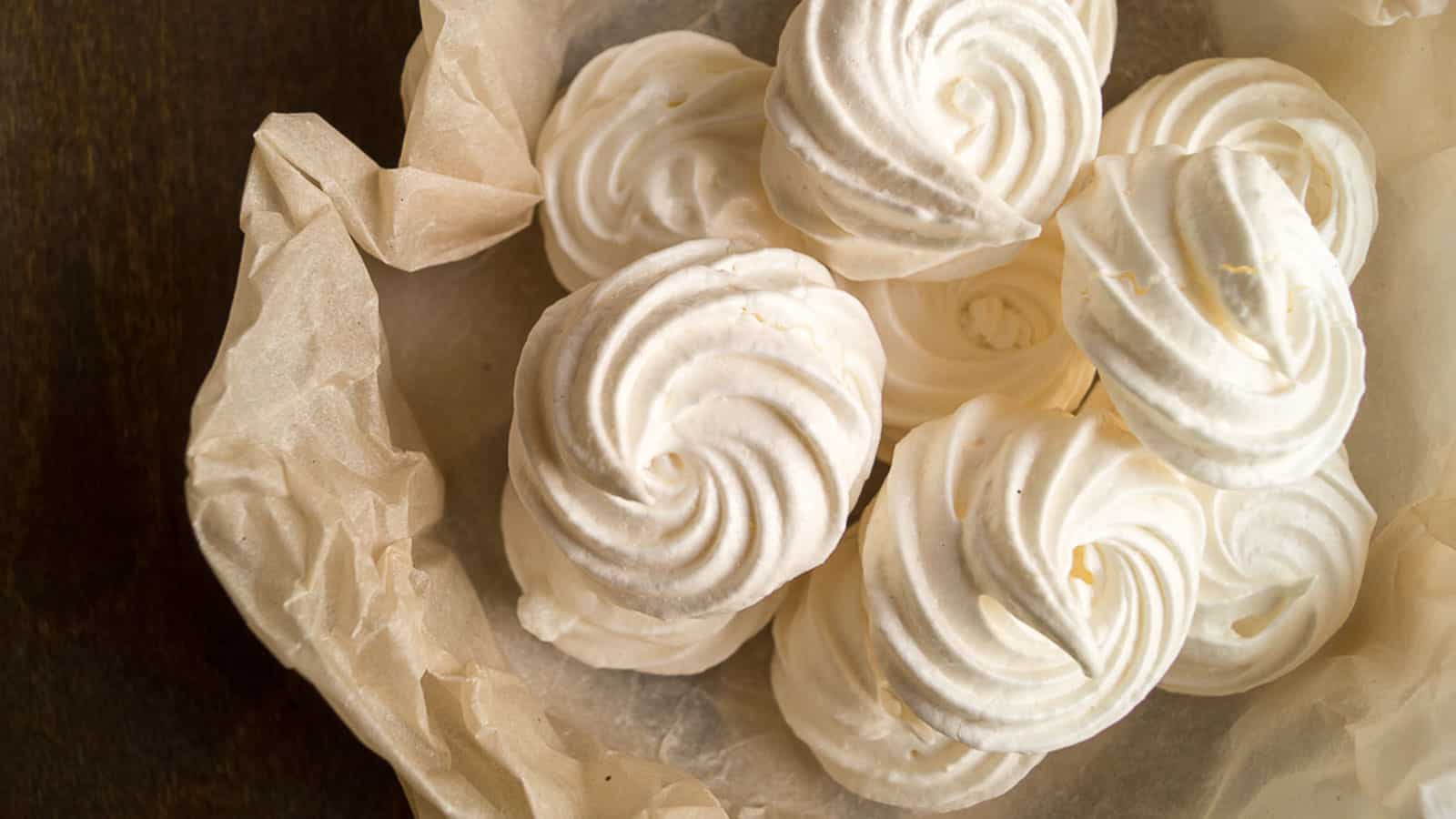 Meringue on crumpled parchment paper bag on a wooden table.