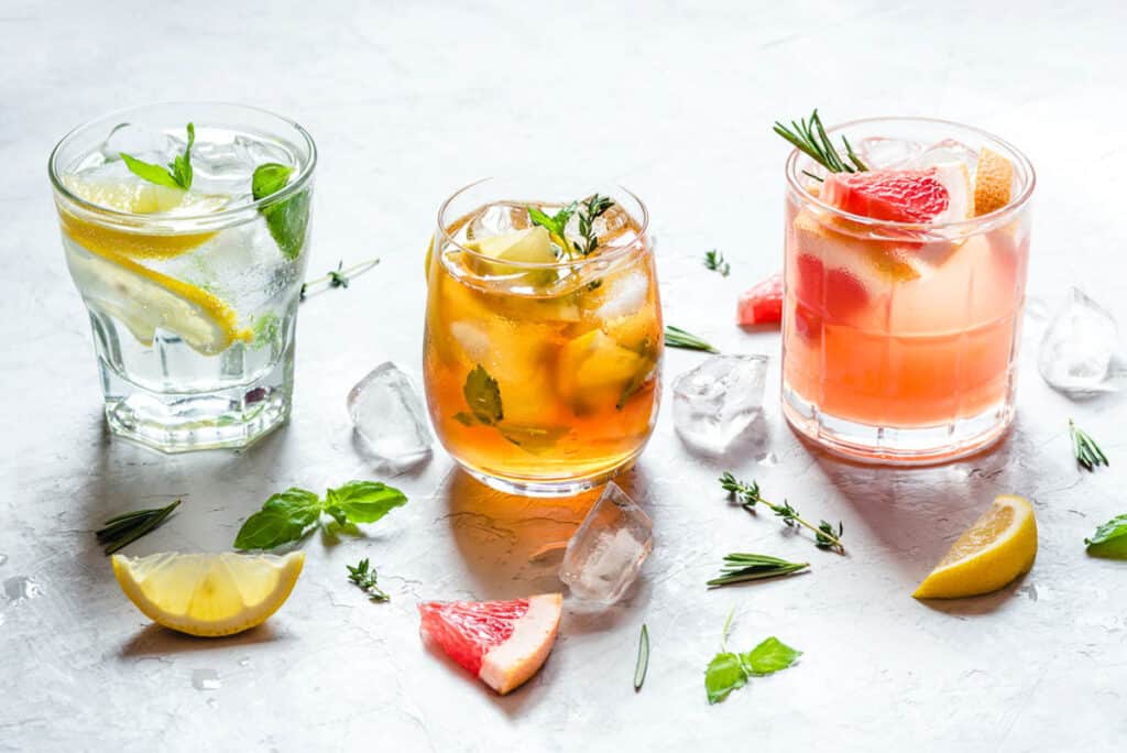 Four drinks with lemon, grapefruit, mint and ice.