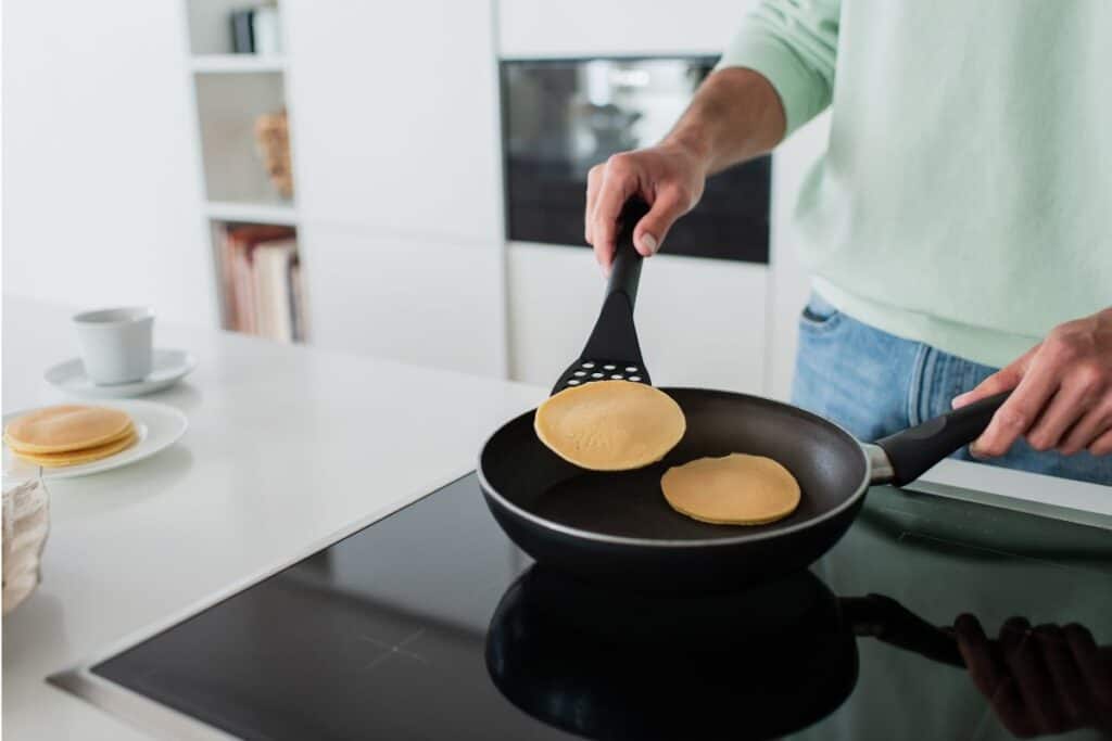 In celebration of National Pancake Day, a man skillfully fries an array of delicious pancakes on a hot frying pan.