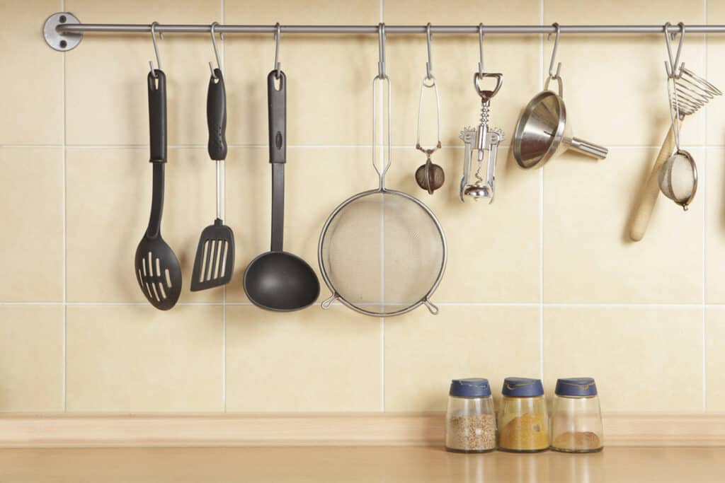 A kitchen with utensils hanging on a rack.
