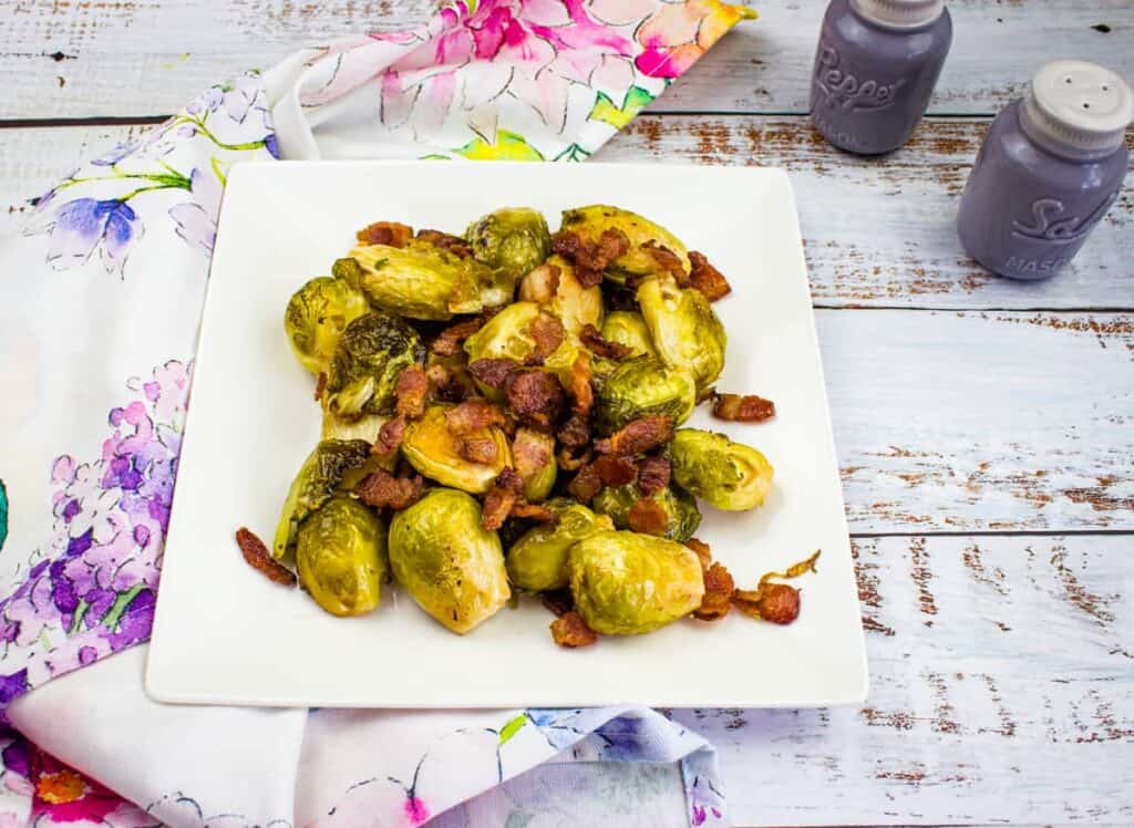 Brussels sprouts with bacon on a white plate.