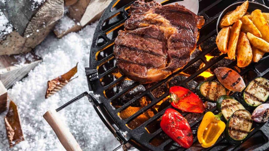 Winter grilling: Enjoy a sizzling experience as steak and vegetables are cooked on a grill amidst the snowy backdrop.