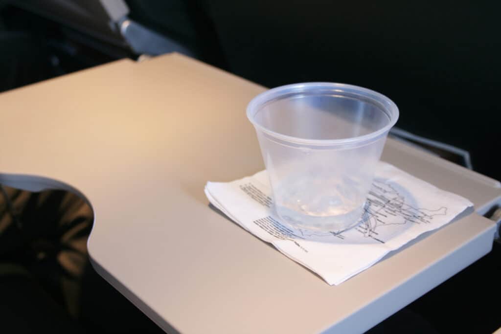 Plastic cup with remnants of a beverage on an airplane tray table.