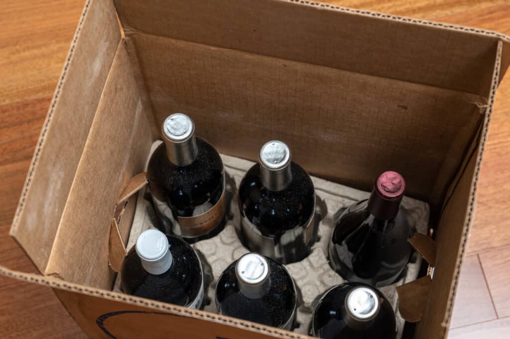 A cardboard box with a set of six assorted wine bottles, viewed from above.