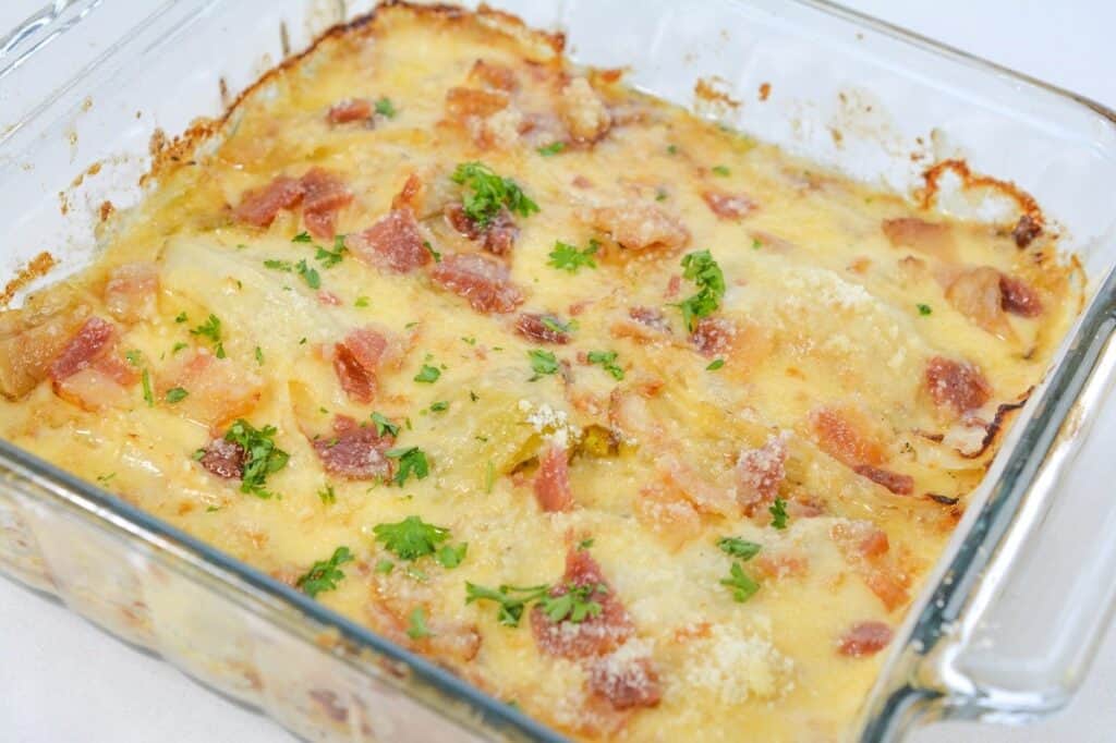 Baked cheese and bacon casserole garnished with parsley in a glass dish.