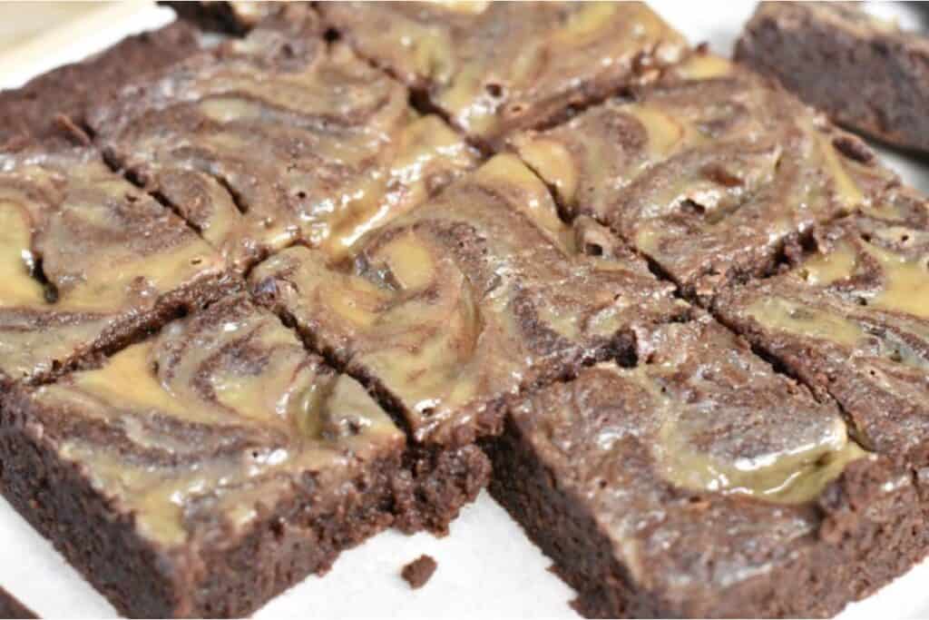 Freshly baked brownies with a swirled icing topping.