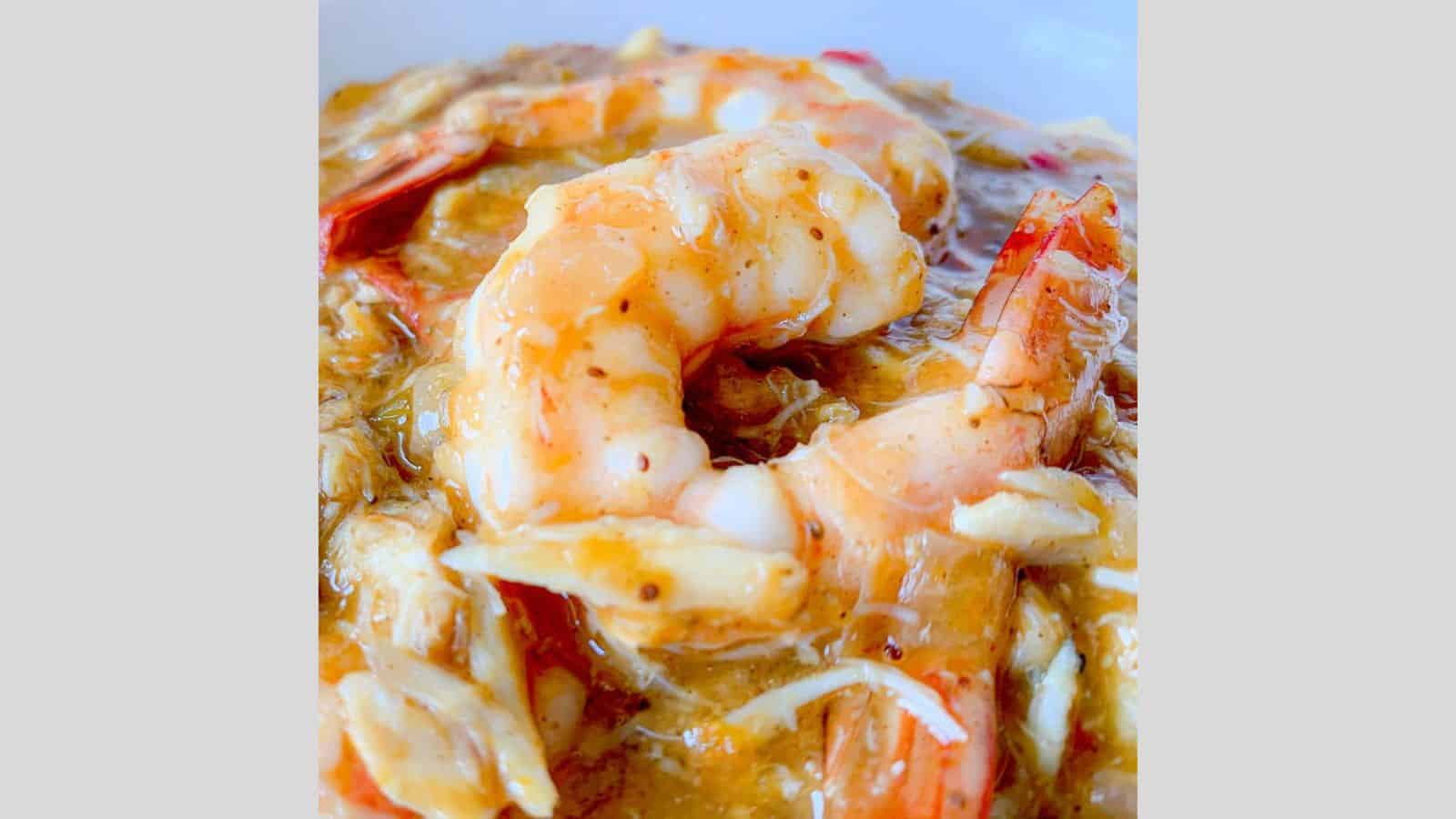 A large shrimp in a sea of crab gravy atop cheese grits.