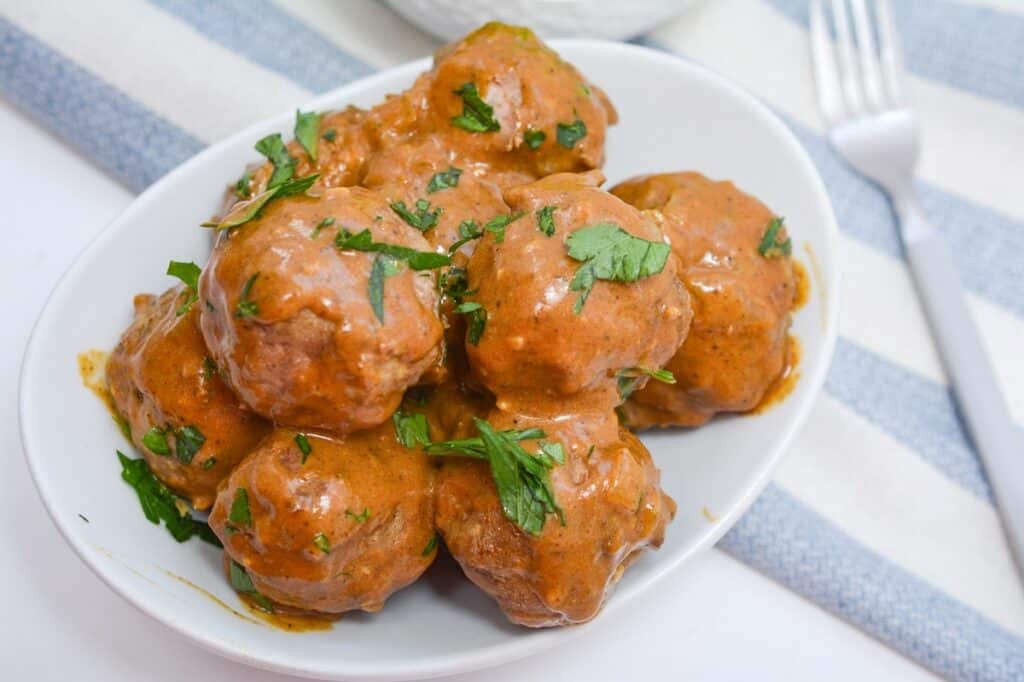 A plate of meatballs garnished with parsley in a tomato-based sauce.