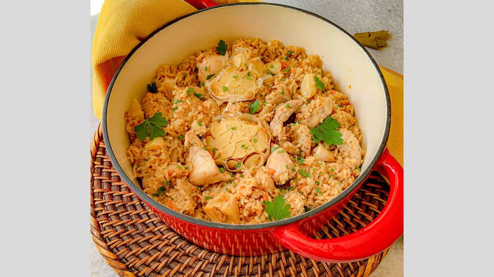 A Dutch oven filled with chicken and rice pilaf with garlic and spices.