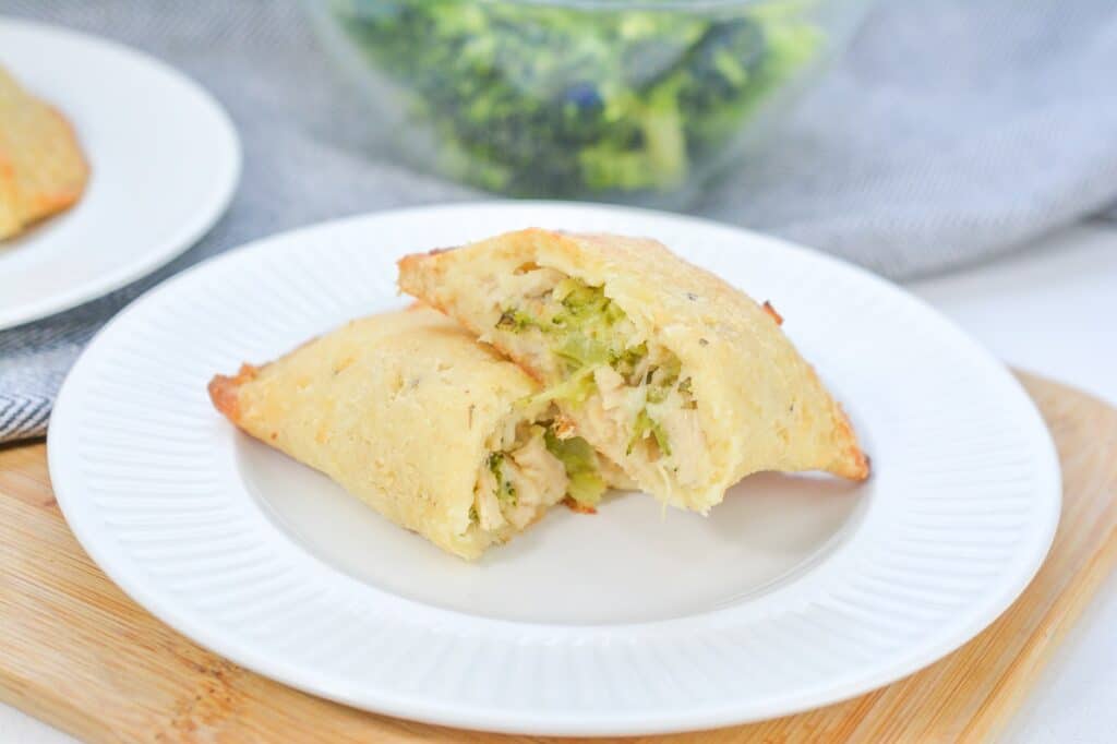A chicken and broccoli-stuffed pastry cut in half on a white plate.