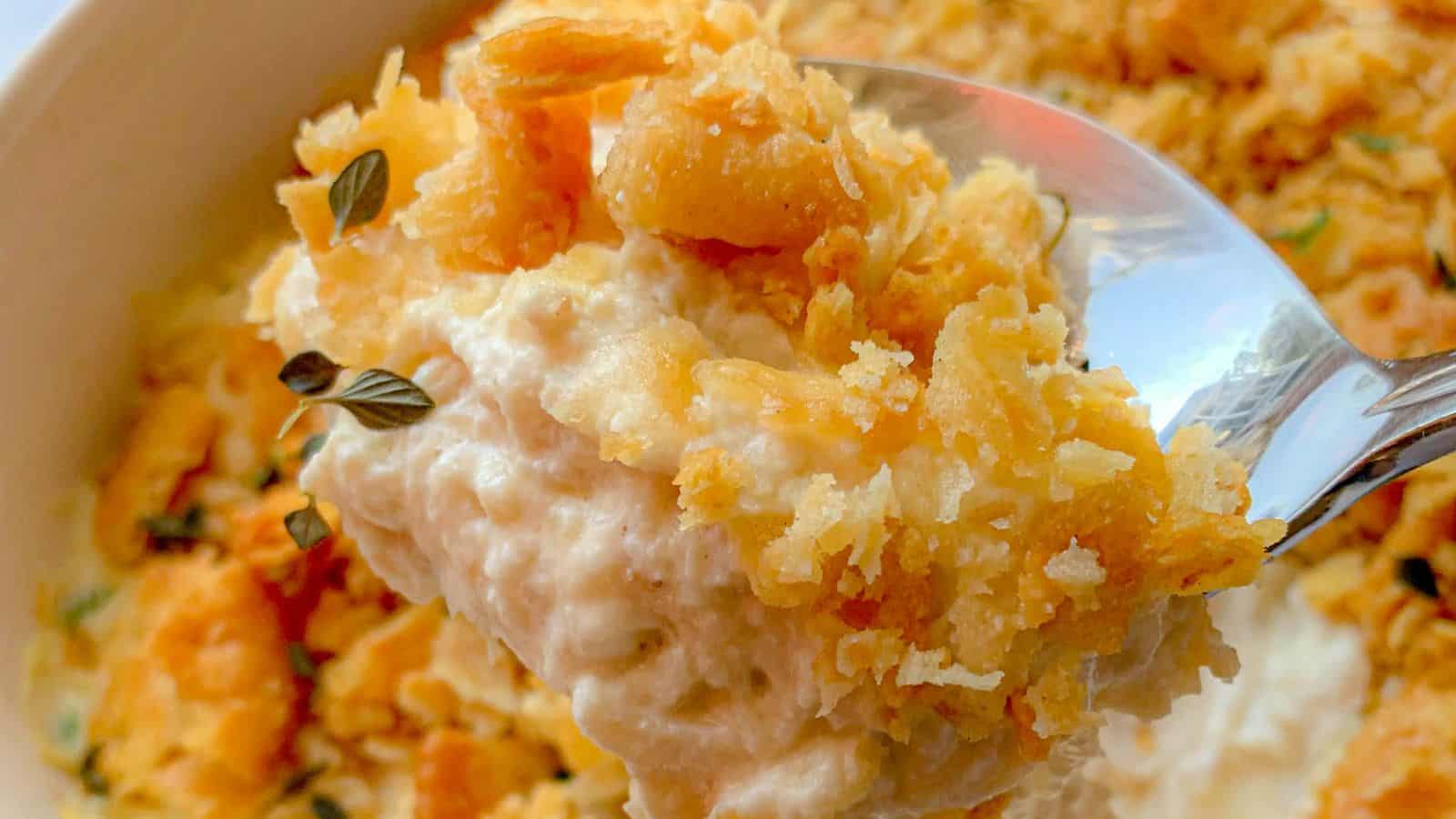 A spoonful of chicken casserole with a Ritz cracker topping.