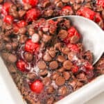 A dish with chocolate chips and cherries in it.