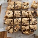 Freshly baked chocolate chip blondies cut into squares on parchment paper.
