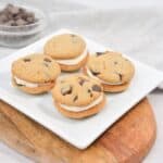 Chocolate chip cookies with cream filling on a white plate.