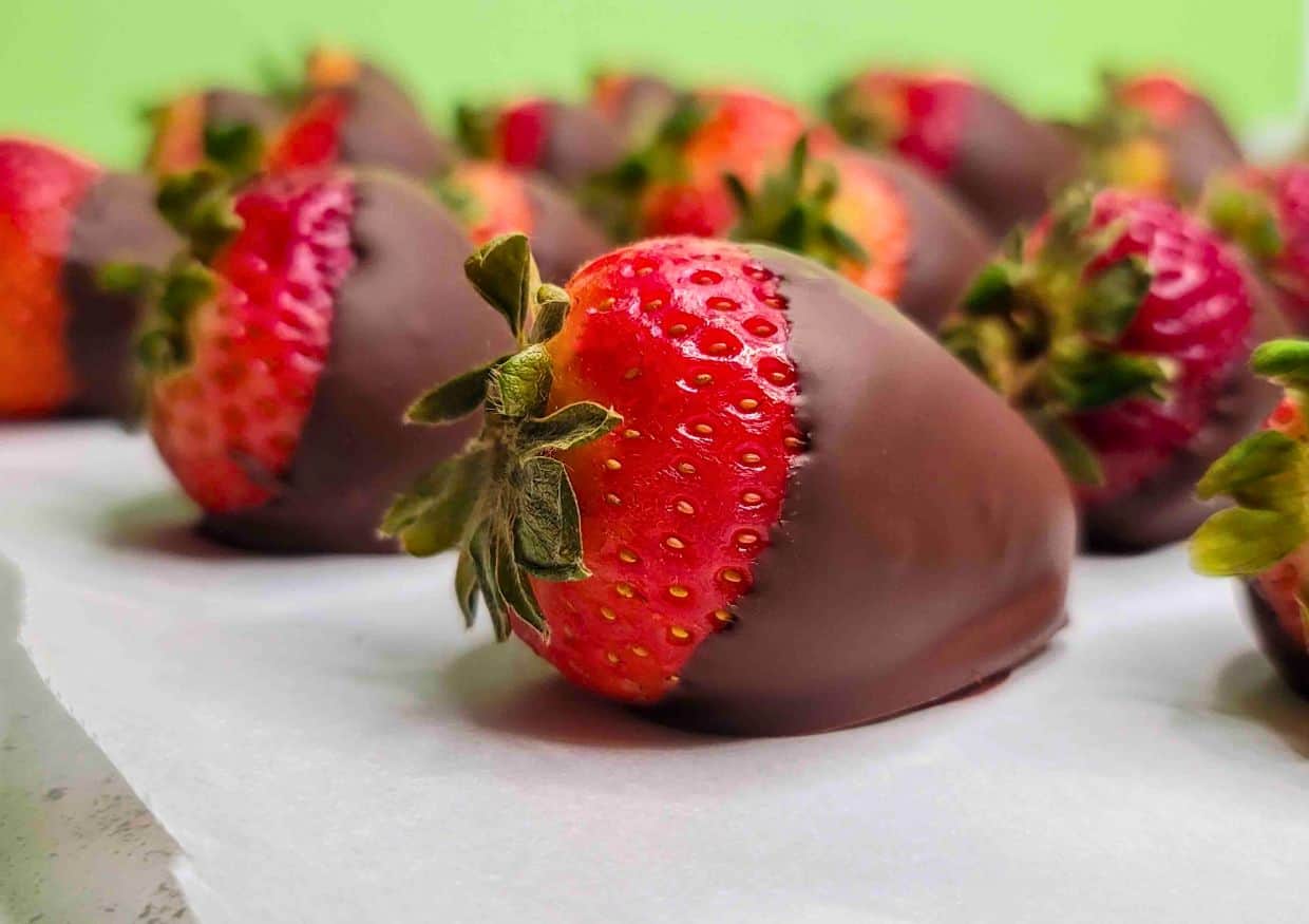 Rows of chocolate covered strawberries on parchment paper.