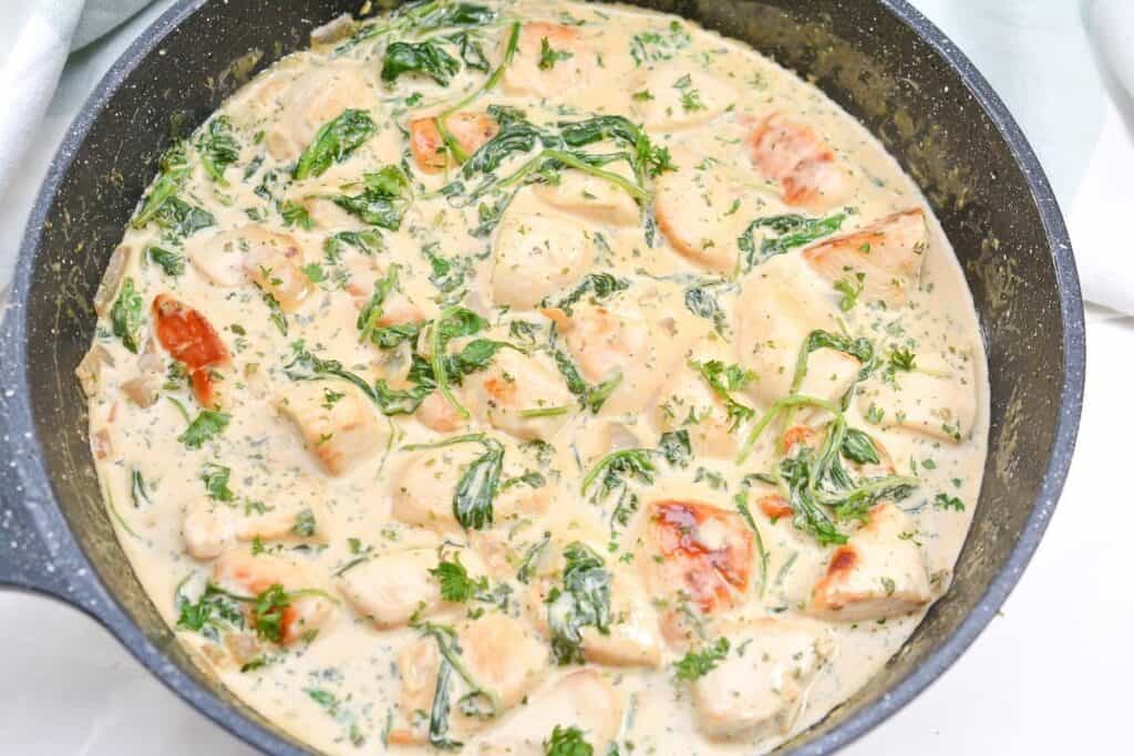 Creamy chicken and spinach skillet meal with tomatoes.