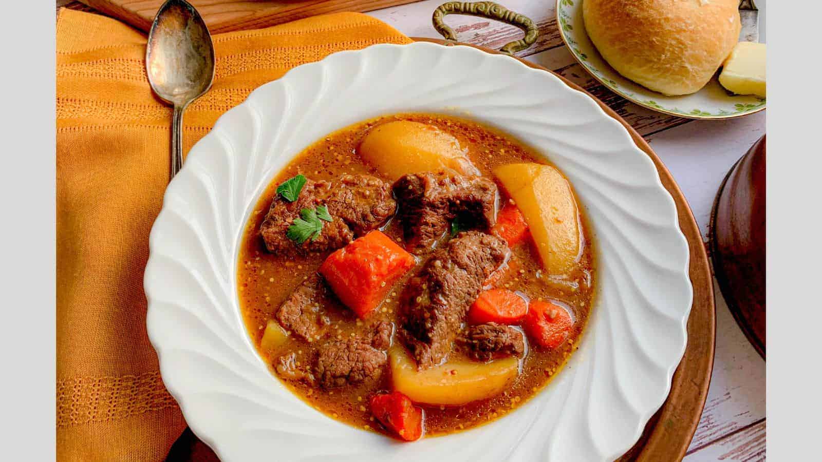 A bowl of thick beef stew with carrots and potatoes.