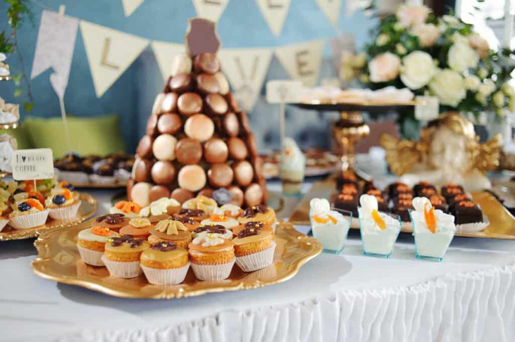 Table set with a variety of desserts, featuring cupcakes and a chocolate-covered strawberry pyramid, at a festive event.
