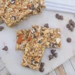 Homemade granola bars with nuts and chocolate chips on a marble surface.