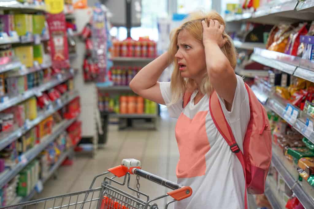 Woman looking confused while shopping in a grocery store aisle.