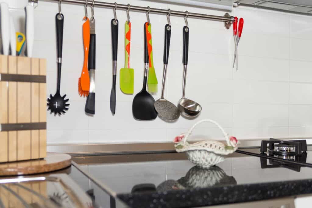Utensils hanging from a rack in a kitchen.