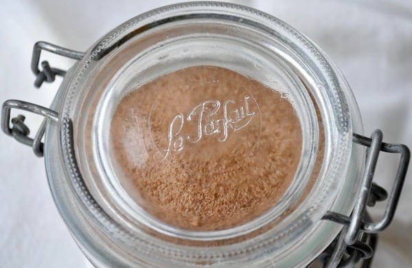 A close-up view of a glass jar with a metal clasp lid, containing a brown powdery substance, marked with the logo "le parfait.