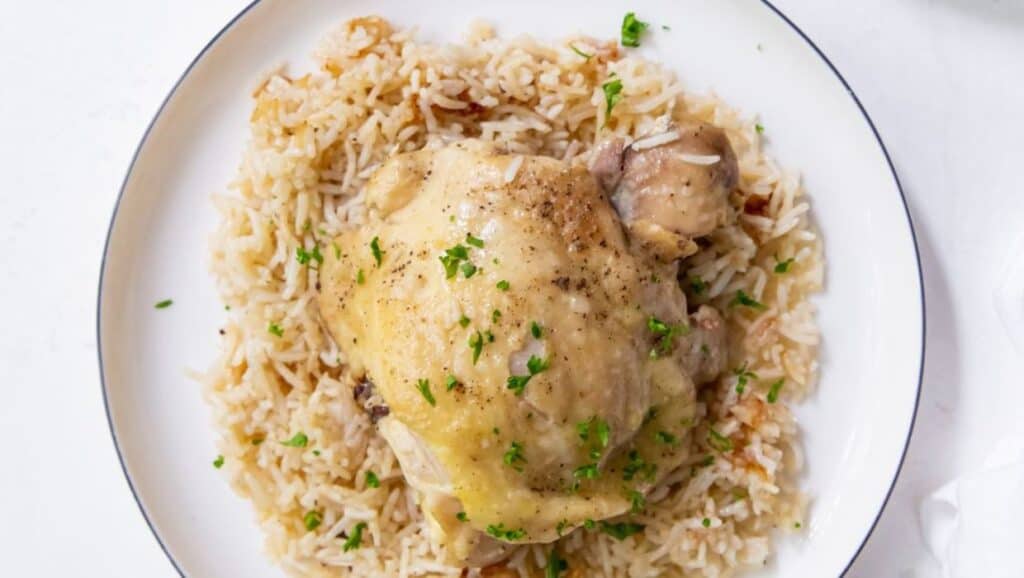 A plate of chicken and rice garnished with herbs.