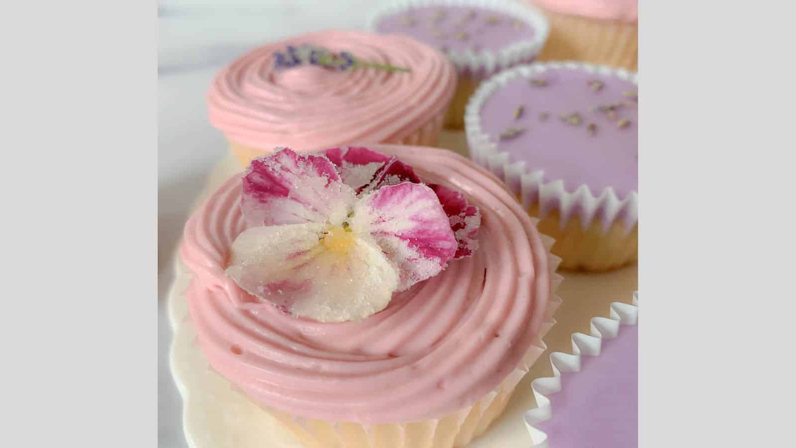 Cupcakes adorned with a swirly frosting and sugared, edible flowers.