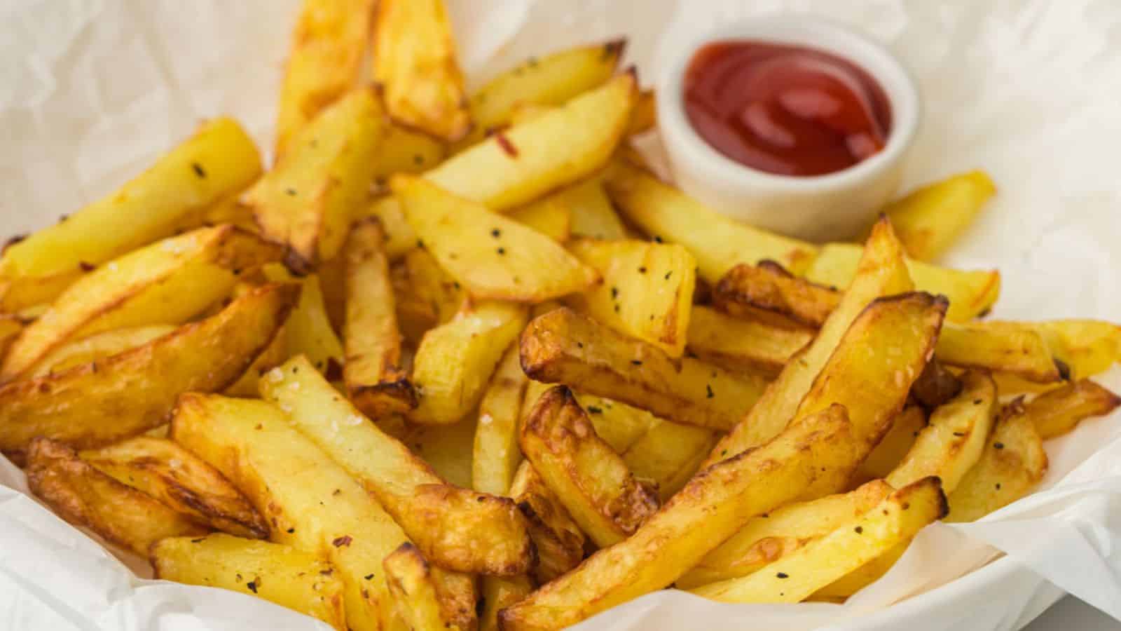 A serving of golden-brown french fries with a side of ketchup.