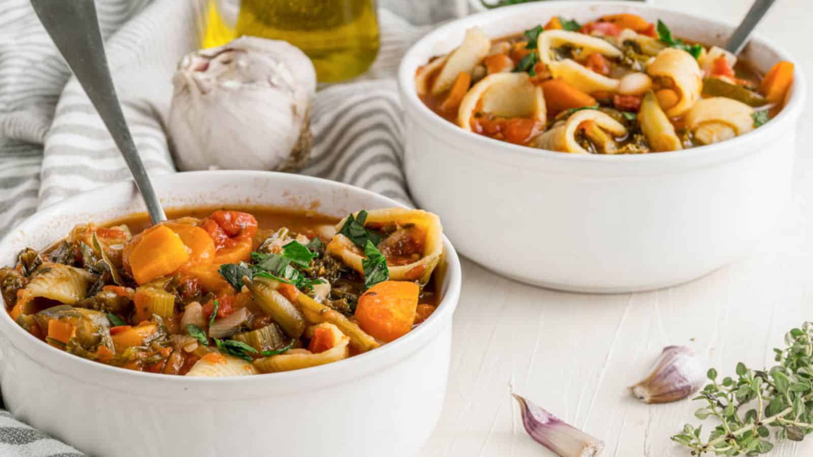 Two bowls of soup with pasta and vegetables.