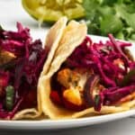 A plate of tacos with red cabbage and cauliflower slaw.