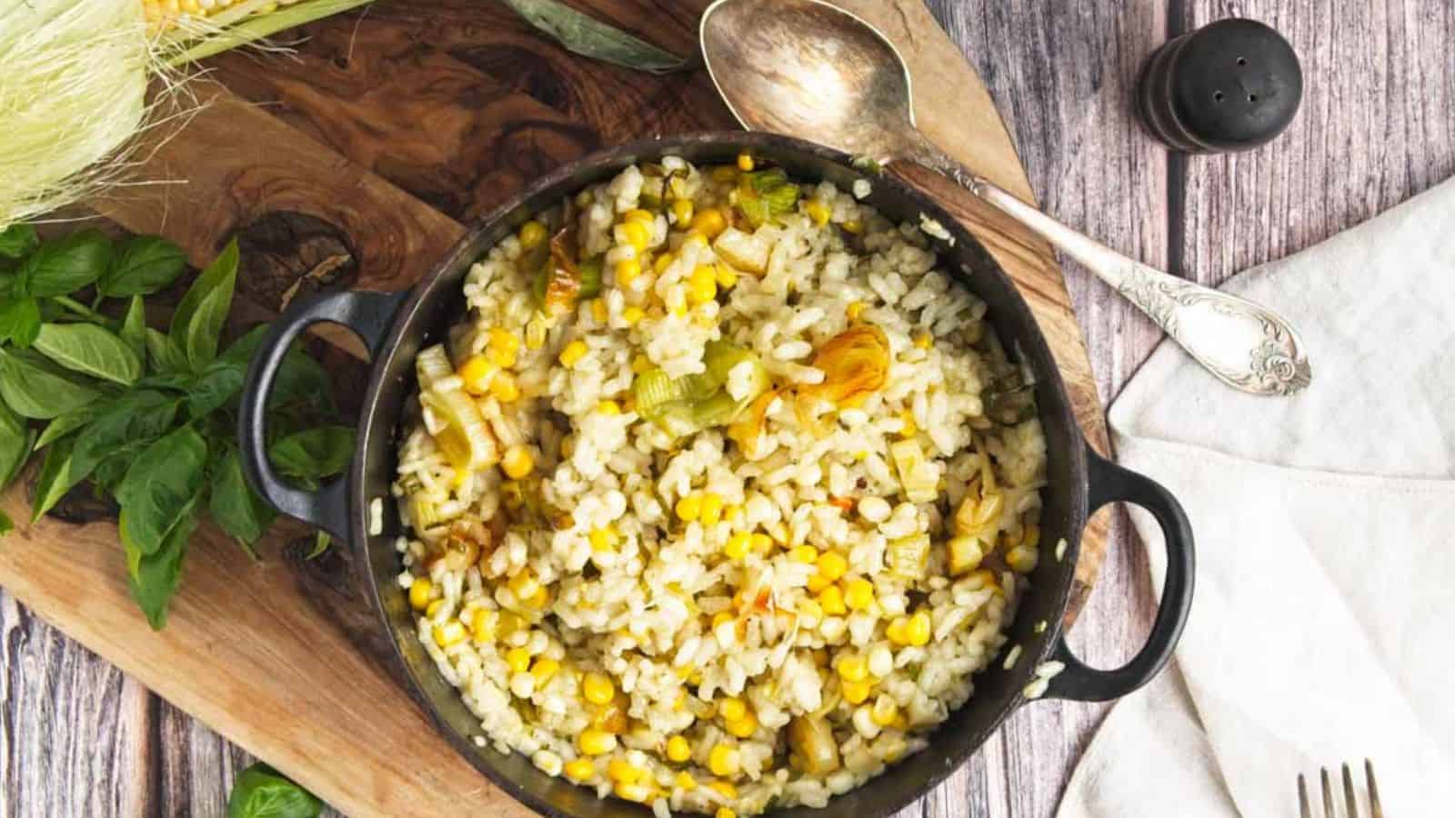 Sweet corn risotto in a skillet on a wooden cutting board.