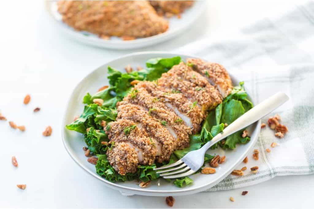 Almond-crusted chicken served on a bed of fresh greens.