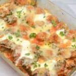 A tray of baked meatballs topped with melted cheese and garnished with fresh herbs.