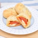 Pepperoni and cheese stuffed bread rolls on a plate with marinara sauce on the side.