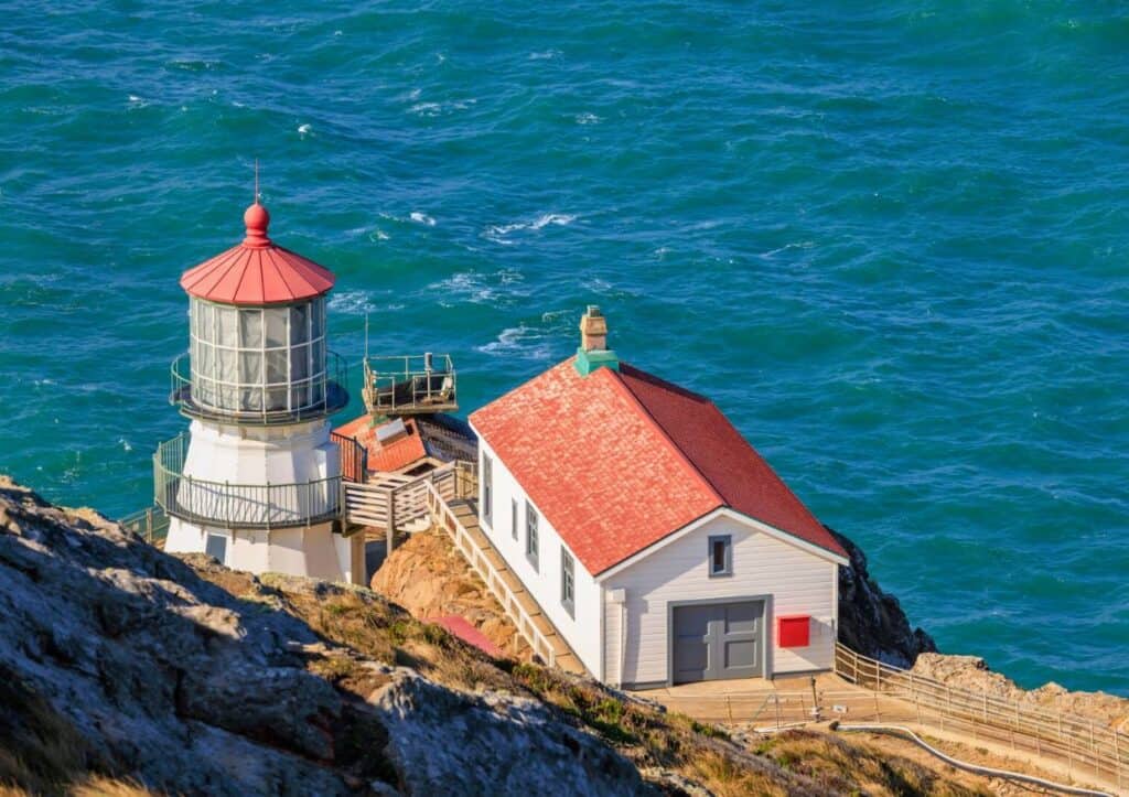 A lighthouse sits on top of a cliff overlooking the ocean in a California national park.