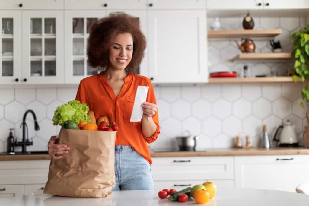 Woman unpacking groceries in kitchen.