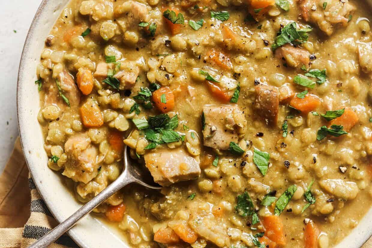 Slow cooker split pea soup in a slow cooker with a spoon.