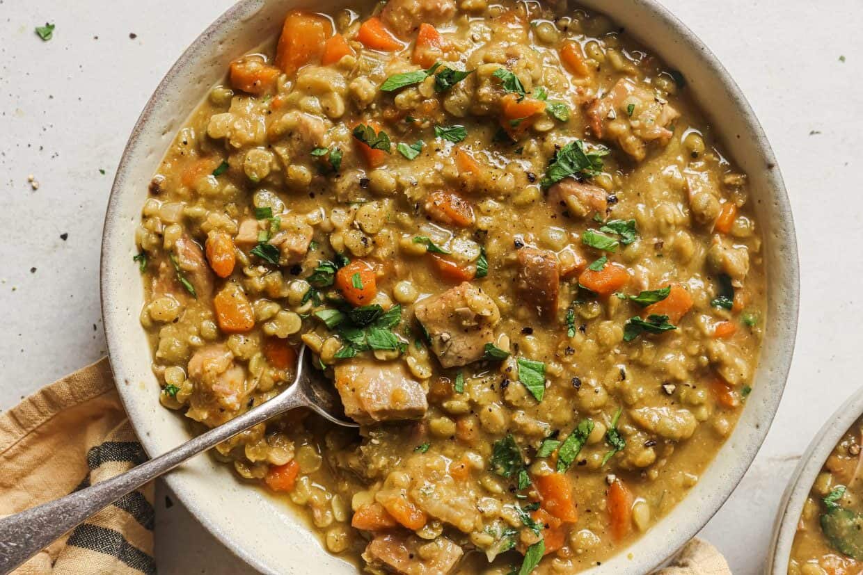 Slow cooker split pea soup in a slow cooker with a spoon.